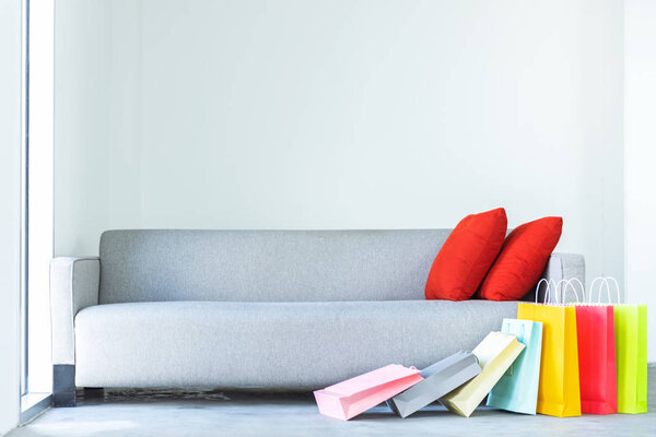 Shopping online. Colorful shopping bags with red pillow on sofa in the living room