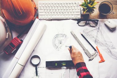 Top View Mimar planı üzerinde çalışıyor. Mimarlar işyeri. Mühendis araçları ve güvenlik kontrolü, planlar, cetvel, radyo, dizüstü bilgisayar ve bölücü pusula. İnşaat Konsepti.