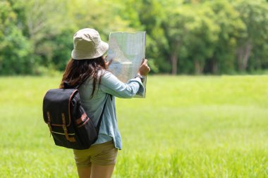 Öğrenci Asyalı kadın ve sırt çantası macera ile gezgin çalışma ve eğitim doğa için orman ormanda açık yön bulmak için harita tutan. Seyahat ve Yaşam Tarzı Kavramı