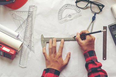 Top View Mimar planı üzerinde çalışıyor. Mimarlar işyeri. Mühendis araçları ve güvenlik kontrolü, planlar, cetvel, radyo, dizüstü bilgisayar ve bölücü pusula. İnşaat Konsepti.