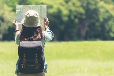 Öğrenci Asyalı kadın ve sırt çantası macera ile gezgin çalışma ve eğitim doğa için orman ormanda açık yön bulmak için harita tutan. Seyahat ve Yaşam Tarzı Kavramı