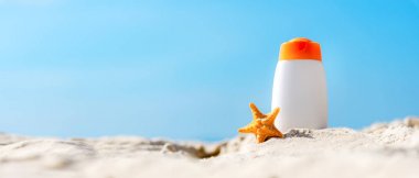 Tropikal plajda deniz yıldızı ile beyaz plastik şişelerde sağlıklı bakım cilt kadın için koruyucu güneş kremi veya güneş kremi ve güneşte losyon, tatil yaz aksesuarları, metin banner için kopya alanı. Yaz cONCEP