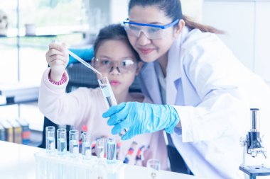 Asya çocukları bilim adamı ile mikroskop değerlendirmek çalışma analiz. Sağlık araştırmacılar damlalık kimyasal test ve yaşam bilimi Laboratuvarı çalışma ile bazı araştırma yapıyor, odak seçin