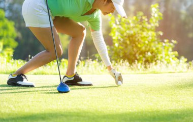 El Asya sportif kadın, sağlıklı spor için zamanında akşam Golf kursu kulüp ile tee Golf topu koyarak. Yaşam tarzı ve spor konsepti