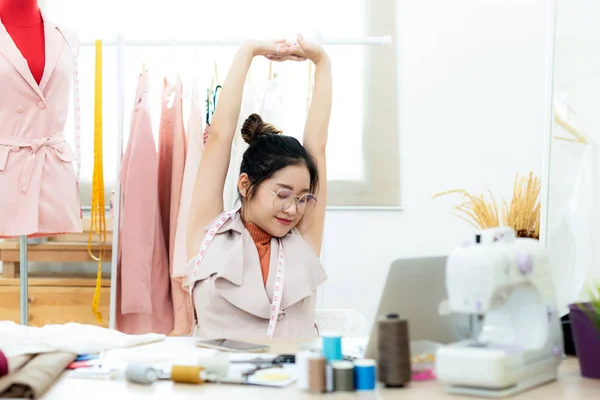 Relax time.  Asian women fashion designer  raise arm relax after working on her designer in the showroom,  Lifestyle Stylish tailor taking measurements on mannequin.  Business and Industry small Concept