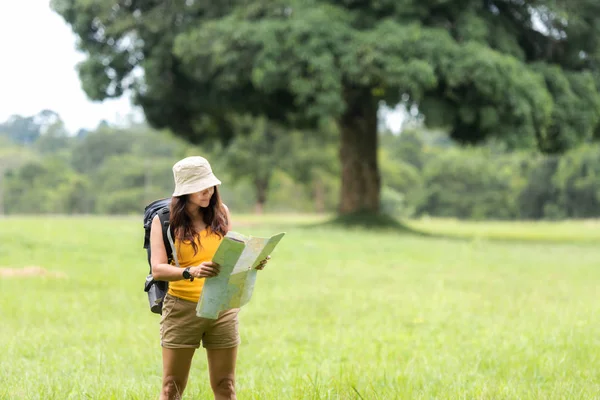 Women hiker or traveler with backpack adventure holding map to find directions and walking relax in the jungle forest outdoor for destination leisure education nature on vacation. Travel and Lifestyle Concept