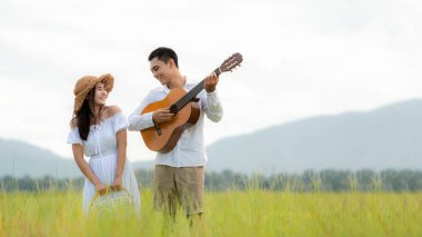 Yaşam tarzı, güneşli piknik zamanı. Asyalı genç çift tatilde çayırlarda rahatça yürüyüp eğleniyor. Romantik ve aşık. Yaşam tarzı kavramı