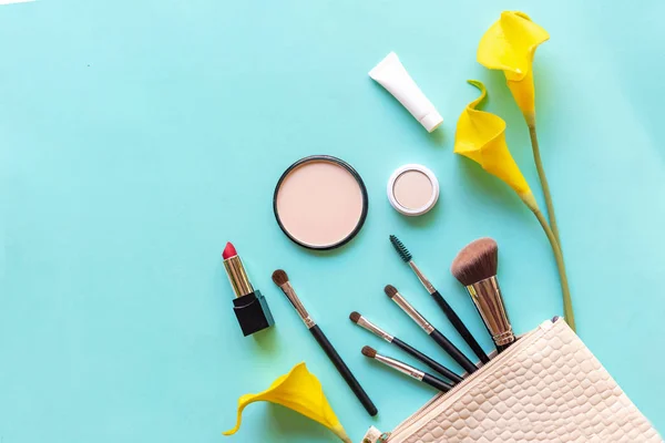 Makeup cosmetics tools and beauty cosmetics gift, products and facial cosmetics package lipstick with yellow lily flower on blue background, top view and copy space.  Lifestyle Beauty Concept