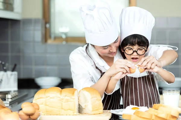 Healthy Family.   Asian little boy help mother cooking toast and make bread in holiday.  People family making and leaning sweet food, so happy and enjoy.  Family and Lifestyle Concept.