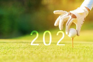 Golfçü kadın, yeni sağlıklı spor, fotokopi alanı için yeşil golfe Mutlu Yıllar 2020 için golf topu koyuyor. Sağlıklı ve Tatil Konsepti.