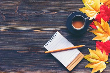 Mevsimlik sonbahar akçaağaç yaprakları. Sıcak kahve buharı tüten sıcak bir eşarp ve tahta masa arkaplanındaki tebrik mesajı için kağıt bir not. Güneşli bir günde rahatla. Yaşam tarzı kavramı