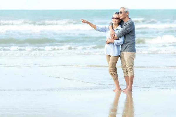 Asian Lifestyle senior couple hug on the beach happy in love romantic and relax time. Tourism elderly family travel leisure and activity after retirement in vacations summer.