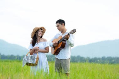 Yaşam tarzı, güneşli piknik zamanı. Asyalı genç çift tatilde çayırlarda rahatça yürüyüp eğleniyor. Romantik ve aşık. Yaşam tarzı kavramı