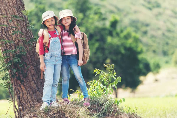 Grup Asyalı aile çocukları kollarını kaldırıp ayakta duruyorlar. Eğitim için dağ ile geziler ve doğa parkında dinlenmek için açık hava, macera ve turizme bakıyorlar. Seyahat tatilleri