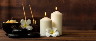 Tayland spa kompozisyonu aroma terapisi mumlar ve ahşap masada Plumeria çiçekleri. Sağlıklı ve Rahat Konsept