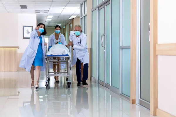Ekip doktoru sedye sedyesi koridorunu kadın hastalarla dolduruyor. Sağlık Hizmetleri Konsepti