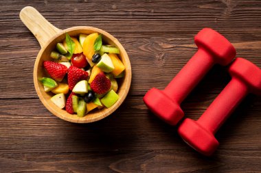 Sağlıklı meyveler. Taze meyve salatası diyeti. Dambıllarla uyumlu. Sağlıklı yaşam tarzı için spor aletleri. Detoks için meyve suyu. Kilo Kaybı ve Diyet Konsepti