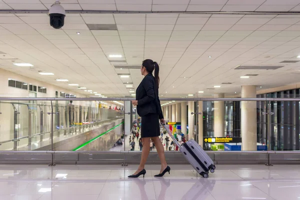 Business woman planning work and meeting trip checking board pass at the airport glass window.  People tourist hold bag luggage near luggage in hall airplane departure