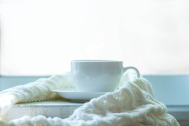 Sıcak kış güneşli arka plan, mevsim ortasında lokum pencere kenarında sıcak örülmüş sepetli süveter. Yaşam tarzı kavramı