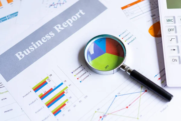 Magnifying glass on pie chart with statistics accounting info which including of many economic statistics business.  Business Concept