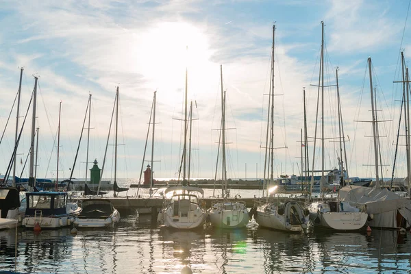 Boats and yachts on the dock in the rays of the setting sun