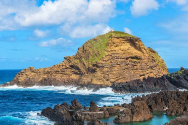 Okyanus dalgaları ve mavi gökyüzü ve volkanik kayaların ön planda arka planı kayalık uçurum