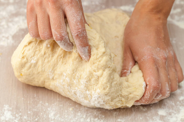 Two hands work with dough on a floured table