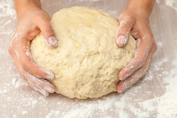Dough in the hands against the background of a floured table