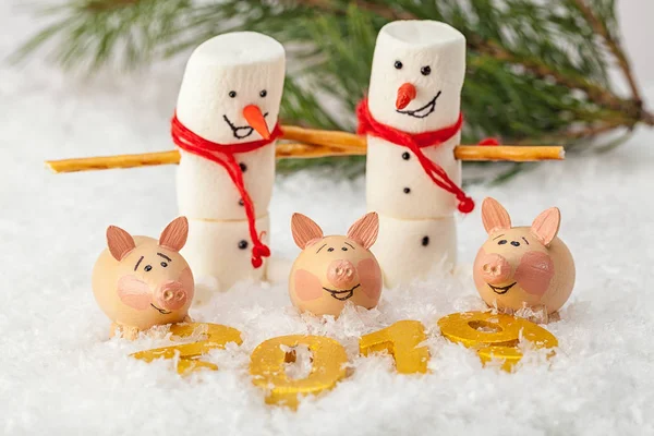 İki kardan adam ve üç domuz bir çam dalı arka plan üzerinde rakamlar 2019 önünde stand