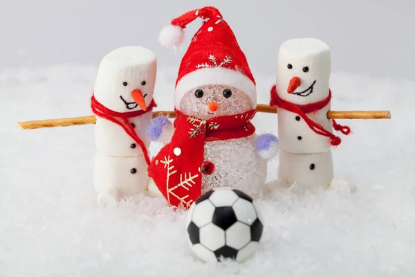 Beyaz kar ve ön planda bir futbol topu üç kardan adam