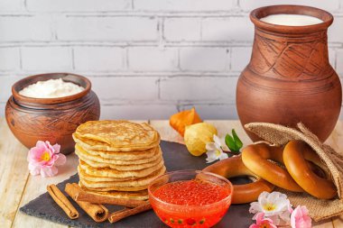 Börek tarçın ve kırmızı havyar kil kapları, simit ve tuğla duvar arka planı siyah seramik tahtasında bolca