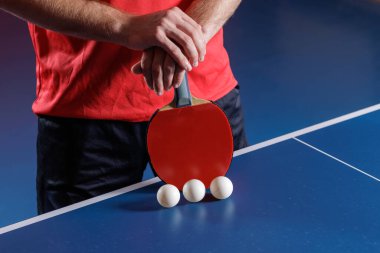Oyuncuların masa tenisini hazırlarken kırmızı raket ve mavi masada üç top kapalı masa eğitimi ve yarışma konsepti.