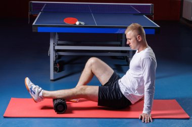 Masa tenisi atleti içeride idman sonrası sünger paten kullanıyor.