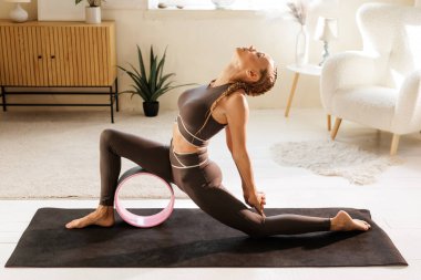 Kalçaları ve göğsü açmak için yoga tekerleği kullanan kadın omurga hareketliliğini ve evdeki duruşunu geliştiriyor.