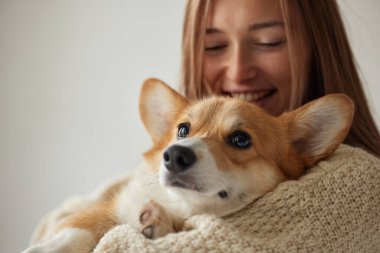 Corgisini evinde kucaklayan bir kadının yakın çekimi, sıcak yaşam tarzı, aşkı, güveni ve arkadaşlığı ifade ediyor..
