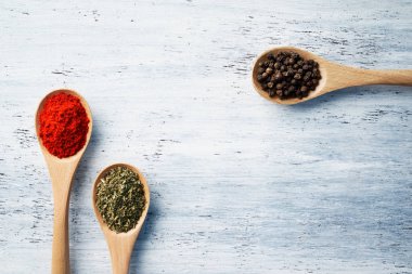 Tahta kaşık, beyaz boyalı masada bitkilerle ve baharatlarla dolu.