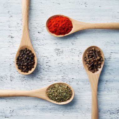 Tahta kaşık, beyaz boyalı masada bitkilerle ve baharatlarla dolu.