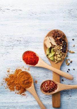 Tahta kaşık beyaz boyalı masada baharatlarla dolu.