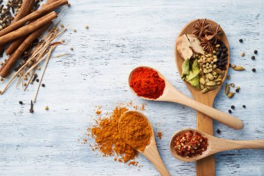 Tahta kaşık, beyaz boyalı masada bitkilerle ve baharatlarla dolu.