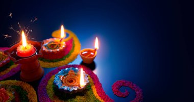 Oil lamps lit on colorful rangoli during diwali celebration clipart