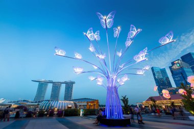 İnsanlar geceleri modern şehirde ışık kurulumunun yanında oturuyorlar.