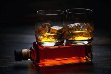 Seçici odak gözlük ahşap masa üzerinde soğuk viski. Tam bir şişe viski