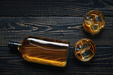 İki bardak buz ve viski siyah ahşap bir masa üzerinde. Tam botlle