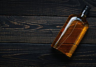 Tam bir şişe viskiyle siyah ahşap bir masa. Yatay konumu