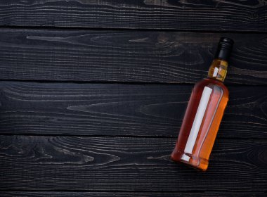 Tam bir şişe viskiyle siyah ahşap bir masa. Yatay konumu