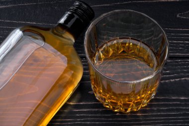 Tam bir şişe viskiyle siyah ahşap bir masa. Yatay konumu