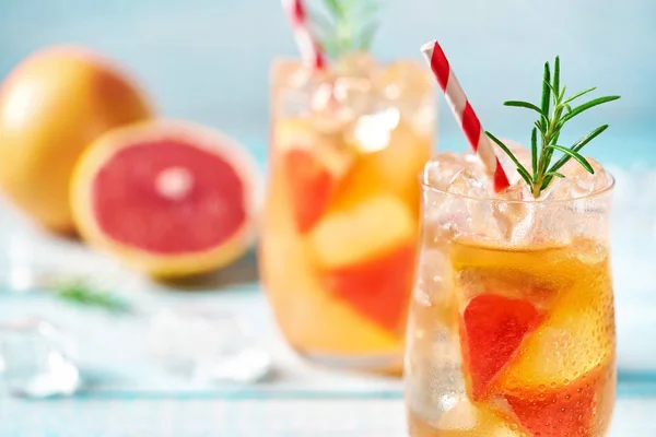 Cold cocktail with grapefruit and rosemary  on a turquoise background,selective focus.