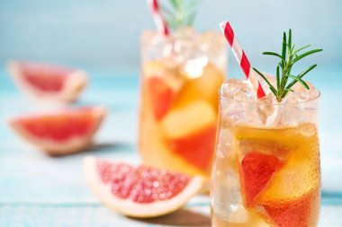 Soğuk kokteyl greyfurt ve biberiye turkuaz bir arka planda seçici odak ile.