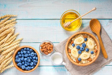 Sağlıklı kahvaltı yulaf gevreği, doğal süt, taze muz, badem ve bal ile. Rustik arka plan. Üstten görünüm.