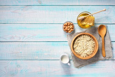 Sağlıklı kahvaltı yulaf gevreği, doğal sütü, badem ve bal ile. Rustik arka plan. Üstten görünüm.